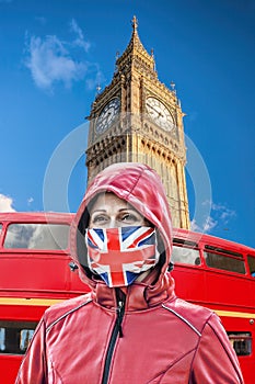 Woman wearing protection face mask with British flag against coronavirus in front of Big Ben, London, England