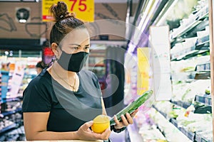 The woman wearing the protective face mask is shopping in the supermarket via the new normal method. the concept of the coronaviru
