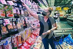 The woman wearing the protective face mask is shopping in the supermarket via the new normal method. the concept of the coronaviru