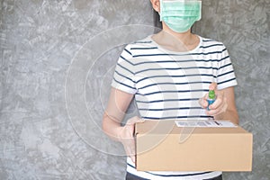 Woman wearing protective mask using spray alcohol sanitizer cleaning parcel post to prevent virus and bacterias from Postal sender