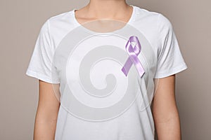 Woman wearing purple ribbon on grey background. Domestic violence awareness