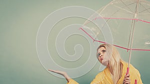 Woman wearing raincoat holding umbrella checking weather