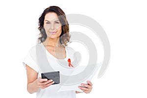 Woman wearing red aids awareness ribbon holding calculator