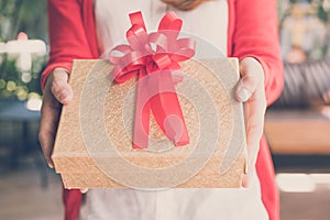 woman wearing red cardigan hold gift box to a man. hand give present box. christmas, new year holiday.