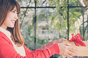 woman wearing red cardigan hold gift box to a man. hand give present box. christmas, new year holiday.