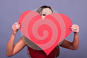 Woman wearing red dress holding big heart sign love symbol