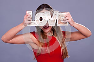 Woman wearing red dress holding sign love symbol