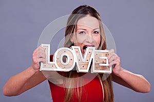 Woman wearing red dress holding sign love symbol