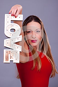 Woman wearing red dress holding sign love symbol