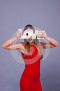 Woman wearing red dress holding sign love symbol