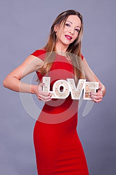 Woman wearing red dress holding sign love symbol