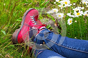 Woman wearing red hiking boots laying on a meadow