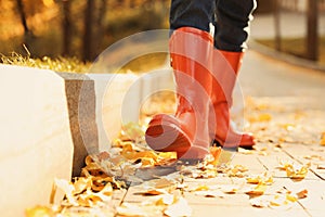 Woman wearing red rubber boots walking in autumn park