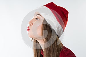 Woman wearing red santa claus hat blows to free copyspace