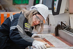 woman wearing safety uniform and hard hat working quality inspection of wood products at workshop manufacturing wooden. female