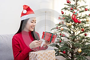 Woman Wearing Santa Claus Hat Holding Xmas Gift Box Near Christmas Tree