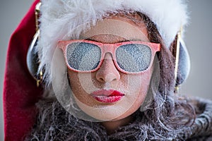 Woman wearing Santa Claus hat and sunglasses listening to music