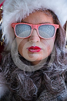 Woman wearing Santa Claus hat and sunglasses listening to music