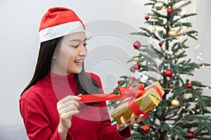 Woman Wearing Santa Claus Hat Unwrap Xmas Gift Box Near Christmas Tree