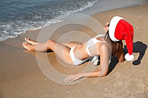 Woman wearing Santa hat and bikini on beach. Christmas vacation