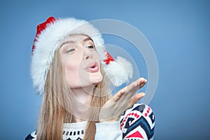 Woman wearing Santa hat blowing at open hand palm with copy space