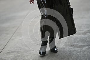 Woman wearing shiny black coat and leather shoes