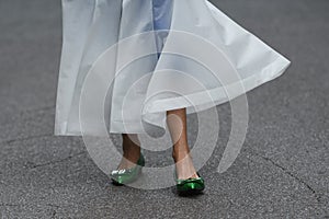 Woman wearing shiny dark green shoes and white transparent dress
