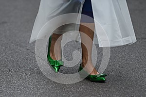 Woman wearing shiny dark green shoes and white transparent dress