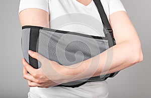 Woman wearing sling to support painful elbow. Overuse, intensive training, tendinitis consequences. Healing process of