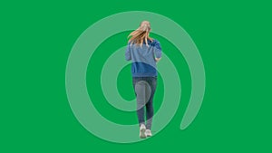 A woman wearing sneakers, blue jeans and a hoodie, running on a green screen. Back view of a full length woman jogging