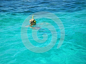 Woman wearing snokeling mask swimming next to tropical island