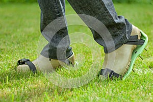 Woman wearing spiked lawn revitalizing aerating shoes, gardening concept