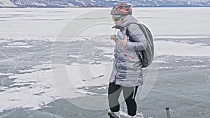 Woman is wearing sports equipment. The girl is dressed in a silvery down jacket, cycling backpack and helmet. Ice of the