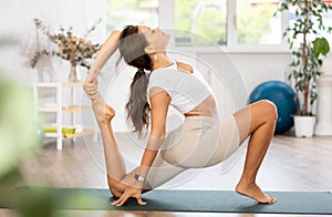 Woman wearing sportwear doing Yoga exercise, Yoga One Legged King Pigeon pose or Eka Pada Rajakapotasana, calm of