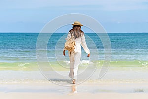 Woman wearing straw hat with bag standing on beach