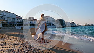 Woman wearing straw hat and white dress on shoreline at Spetses, Greece