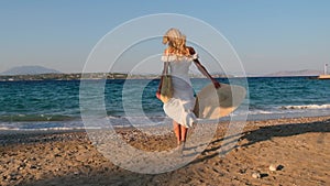 Woman wearing straw hat and white dress on shoreline at Spetses, Greece