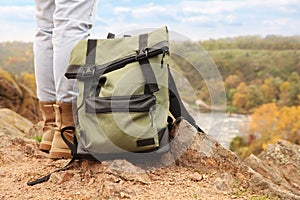 Woman wearing stylish hiking boots with backpack on steep cliff, closeup