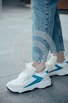 A woman wearing stylish sporty sneakers on the street .Women`s sports shoes. Fashionable sneakers on female legs