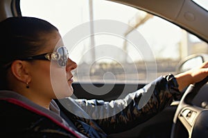 Woman wearing sunglasses drives car and is concentrated looks at road