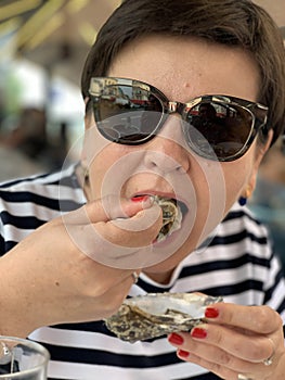 Woman Eating A Fresh Oyster On The Half Shell In Food Court Of A Seafood Market In Trouville, France photo