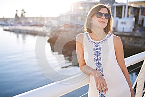 Woman wearing sunglasses and summer dress next to water