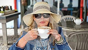 Woman wearing sunhat and sunglasses, drinking coffee from a huge coffeecup photo