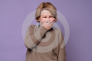 Woman wearing sweate laughing and embarrassed giggle covering mouth with hands