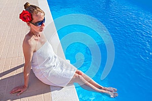 Woman wearing towel with feet in swimming pool