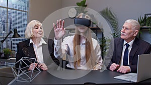 Woman wearing virtual reality glasses tries 3D app for VR helmet while colleagues supporting her