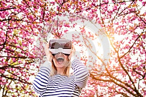 Woman wearing virtual reality goggles outside in spring nature