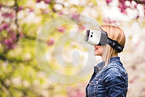 Woman wearing virtual reality goggles outside in spring nature