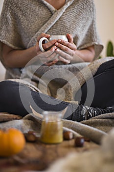 Woman wearing warm cosy clothes drinking mug of hot chocolate in autumn