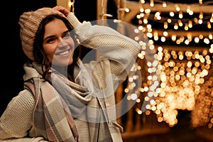 Woman wearing warm sweater, hat and scarf  outdoors at night. Winter season